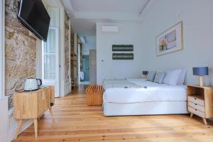 a bedroom with a bed and a flat screen tv at Casa da Portagem by PURUS in Coimbra