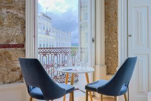 a table and chairs in a room with a window at Casa da Portagem by PURUS in Coimbra