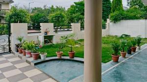 a patio with a pool with plants in pots at Vijay Mansion Pratap Enclave in Jaipur