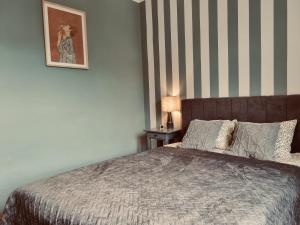 a bedroom with a bed and a striped wall at Akacja Centrum Apartament in Rzeszów
