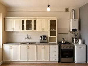 a kitchen with white cabinets and a sink and a stove at Sunshine Boutique Hostel in Yerevan