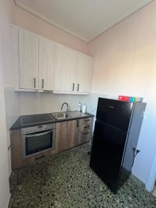 eine Küche mit einem schwarzen Kühlschrank und einer Spüle in der Unterkunft Light Apartment in Ierápetra + 9 Fotos