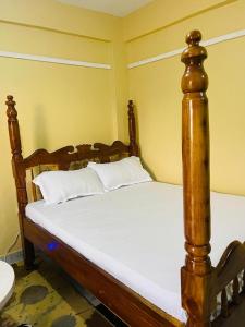 a bed with a wooden frame in a room at Fewa studio in Busia