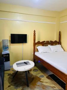 a bedroom with a bed and a tv and a table at Fewa studio in Busia +5 photos