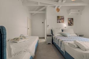 two beds in a room with white walls at Hotel Selini in Agios Nikitas