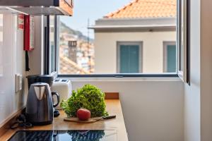 a kitchen counter with an apple on a table in front of a window at Hillside - By WeHost in Funchal
