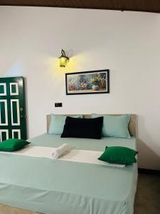 a bedroom with a large white bed with green pillows at Knuckles Breeze Villas Kandy in Kandy