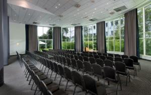 a room with rows of chairs in a building with windows at Wyndham Hannover Atrium in Hannover