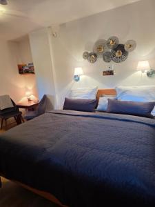 a bedroom with a large bed with blue sheets and pillows at Susann Vendégház in Szigetmonostor