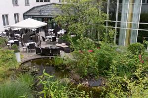 a patio with tables and chairs and a pond at Wyndham Hannover Atrium in Hannover