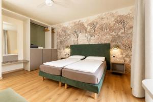 a bedroom with two beds and a mural on the wall at Hotel Alesi in Malcesine