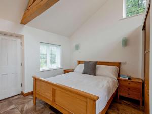 a bedroom with a wooden bed and two windows at 1 Bed in Lymington oc-83370 in Sway