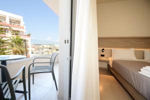 a bedroom with a bed and a balcony with a table at Falassarna Hotel in Chania