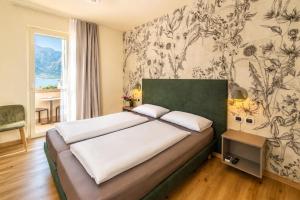 a bedroom with a bed and a wall with floral wallpaper at Hotel Alesi in Malcesine