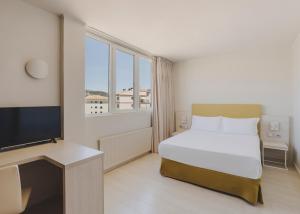 a bedroom with a bed and a flat screen tv at Hotel Mediterráneo in Roses