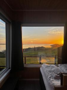 a bedroom with a window with a view of the sunset at Unik og moderne microhytte med utsikt mot havet 40 A Otterlei Resort in Longva