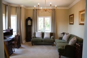 a living room with a couch and a chair and a clock at Redlands Hotel in Pietermaritzburg