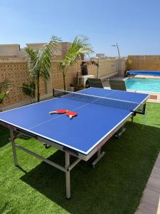 a ping pong table sitting on the grass next to a pool at בית נופש - הדקל והים אילת in Eilat