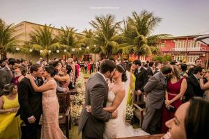 a bride and groom kissing in front of a crowd of people at Pousada Macamirim in Macaíba