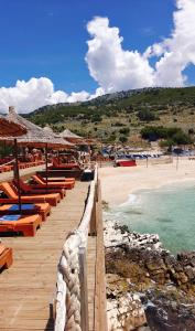 a beach with a bunch of chairs and the ocean at VILLA MARGARIT Boutique Hotel in Sarandë