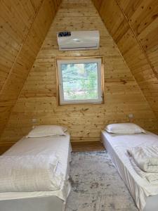 two beds in a wooden room with a window at Eldos_Kolsai in Saty