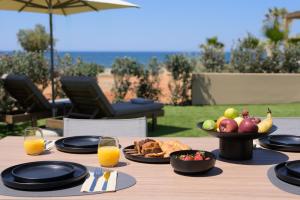 a wooden table with a plate of fruit and juice at NAEMA Seafront Living 2BR Suite in Anissaras +26 photos