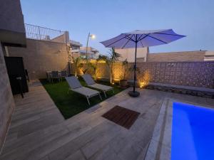 a patio with an umbrella and chairs and a pool at בית נופש - הדקל והים אילת in Eilat