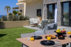a wooden table with plates of food on a patio at NAEMA Seafront Living 2BR Suite in Anissaras