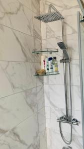 a bathroom with a shower with white marble walls at A cosy & peaceful homestay in Sutton