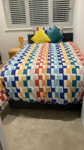 a bed with a colorful quilt on it in a bedroom at A cosy & peaceful homestay in Sutton +13 photos