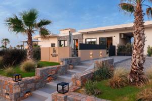 a house with palm trees in front of it at NAEMA Seafront Living 2BR Suite in Anissaras