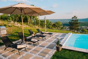 a group of chairs and an umbrella next to a swimming pool at Villa Infinity View in Široki Brijeg