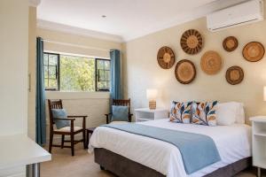 a bedroom with a bed and chairs and a window at Kruger's Retreat & Rest in Marloth Park