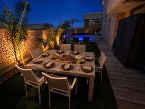 a dining table and chairs in a backyard at night at בית נופש - הדקל והים אילת in Eilat
