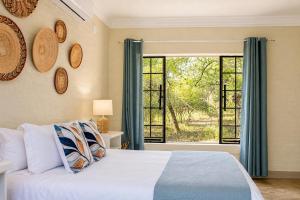 a bedroom with a bed and a large window at Kruger's Retreat & Rest in Marloth Park
