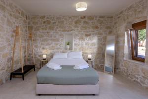 ein Schlafzimmer mit einem Bett und einer Steinwand in der Unterkunft Bastakis Studio Silver in Skalánion