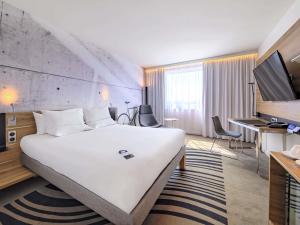 a hotel room with a large white bed and a desk at Novotel Kraków Centrum in Krakow