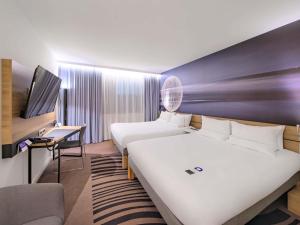 a hotel room with two beds and a tv at Novotel Kraków Centrum in Krakow