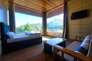 a living room with a large window and a couch at devdaar hills homes cafe & resort in Mussoorie