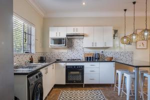 a kitchen with white cabinets and a black counter top at Kruger's Retreat & Rest in Marloth Park