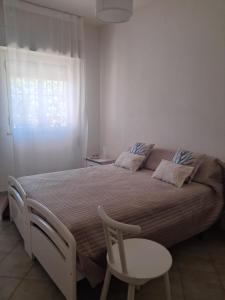 a bedroom with a bed with a chair and a window at Villa Aurora in Ispica