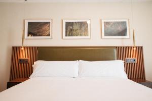 a bedroom with a white bed with three pictures on the wall at Hotel El Nogal in Peligros +59 photos
