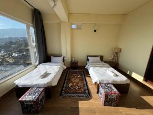 three beds in a room with a large window at The Khaar in Tawang
