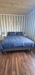 a bedroom with a bed with blue sheets and wood floors at Michel-Inn-Your Scandinavian Escape! in Faggemåla