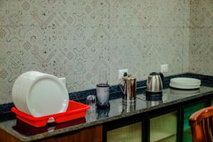 a kitchen counter with a red tray and plates on it at Akruthi Palm Pavilion Resort in Aldūr