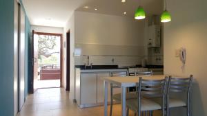 cocina con mesa, sillas y barra en Cabañas Arenas Blandas, en Villa Gesell