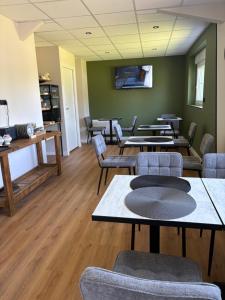 a waiting room with tables and chairs in a building at Hôtel L'escale des Hayons in Esclavelles