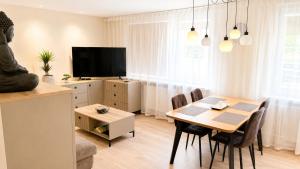 a dining room with a table and a tv at Apartamentai Tarp 7 Ežerų in Zarasai