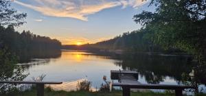 a bench sitting on the shore of a river at sunset at Michel-Inn-Your Scandinavian Escape! in Faggemåla