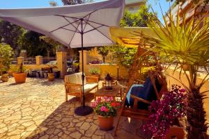 a patio with an umbrella and chairs and flowers at Macri Alghero in Alghero
